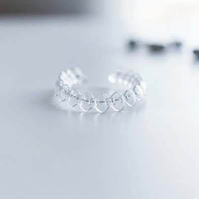 Orthodontic patient smiling confidently with a clear retainer, bright and clean background