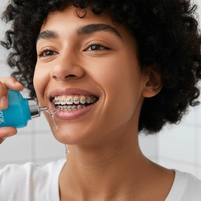 Close-up of a person rinsing with mouthwash, showing clean teeth and braces